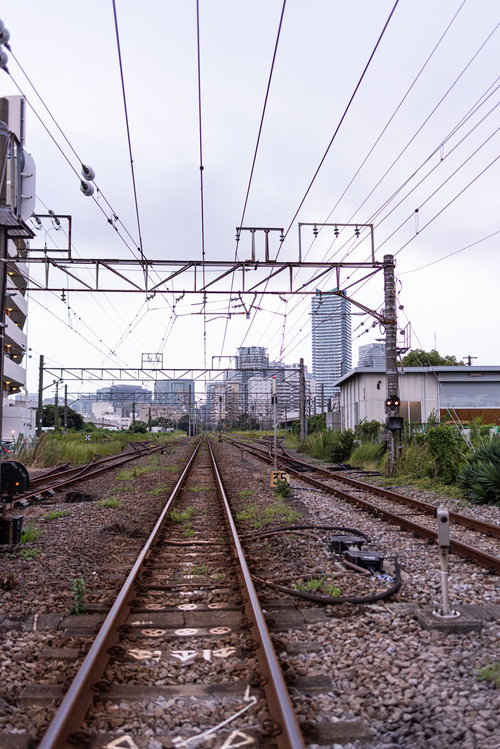 街へと続く線路とレール、架線が張り巡らされた鉄道風景