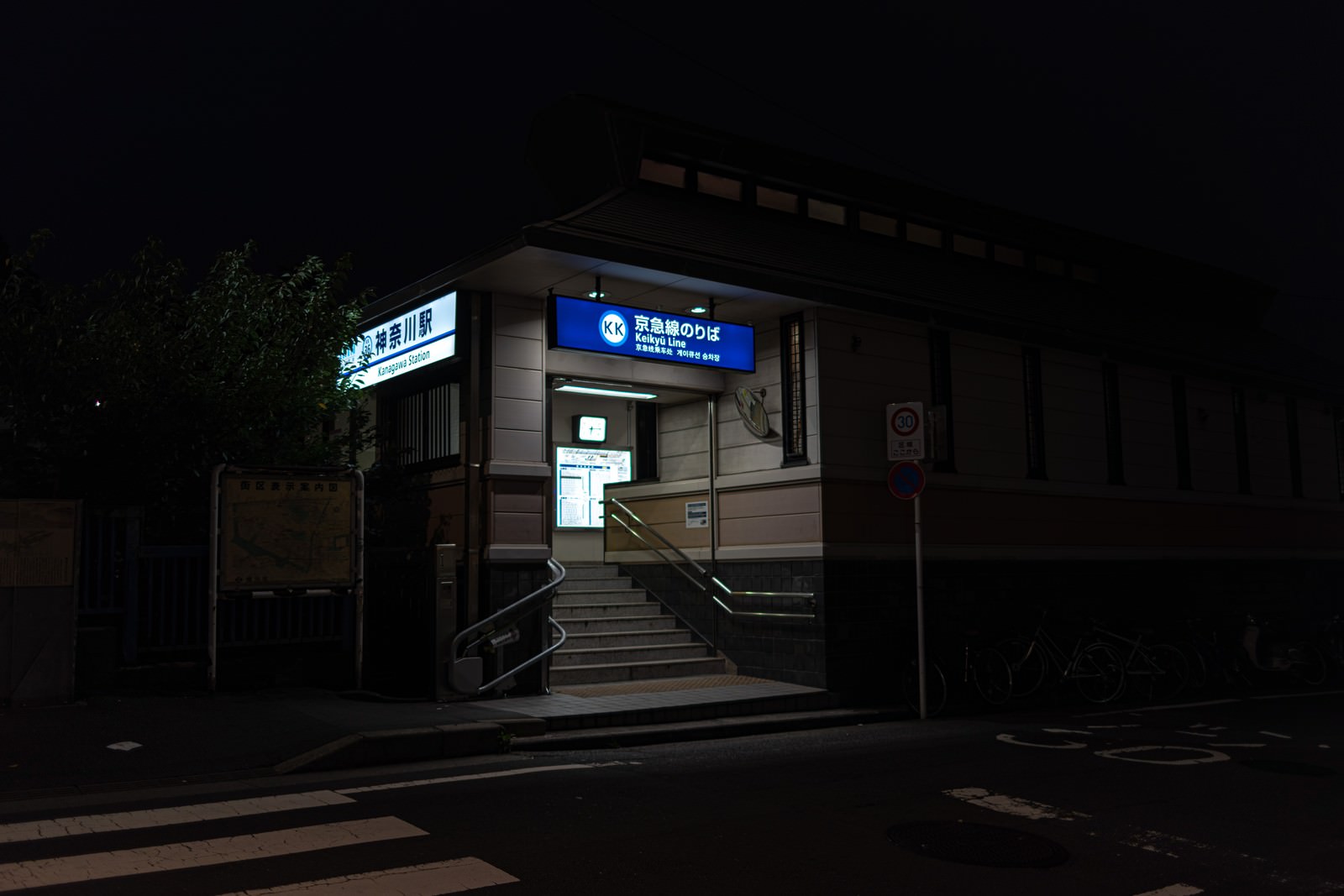 夜の神奈川駅で青い看板が光る階段の風景