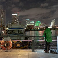 横浜みなとみらいの夜景を背景に夜釣りする人の後ろ姿の写真