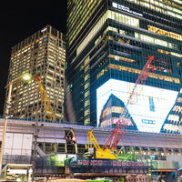 渋谷の夜景に映る工事現場のクレーンと高層ビル群の写真