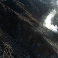 大涌谷の斜面から立ち上がる白い湯気と荒々しい大地の写真