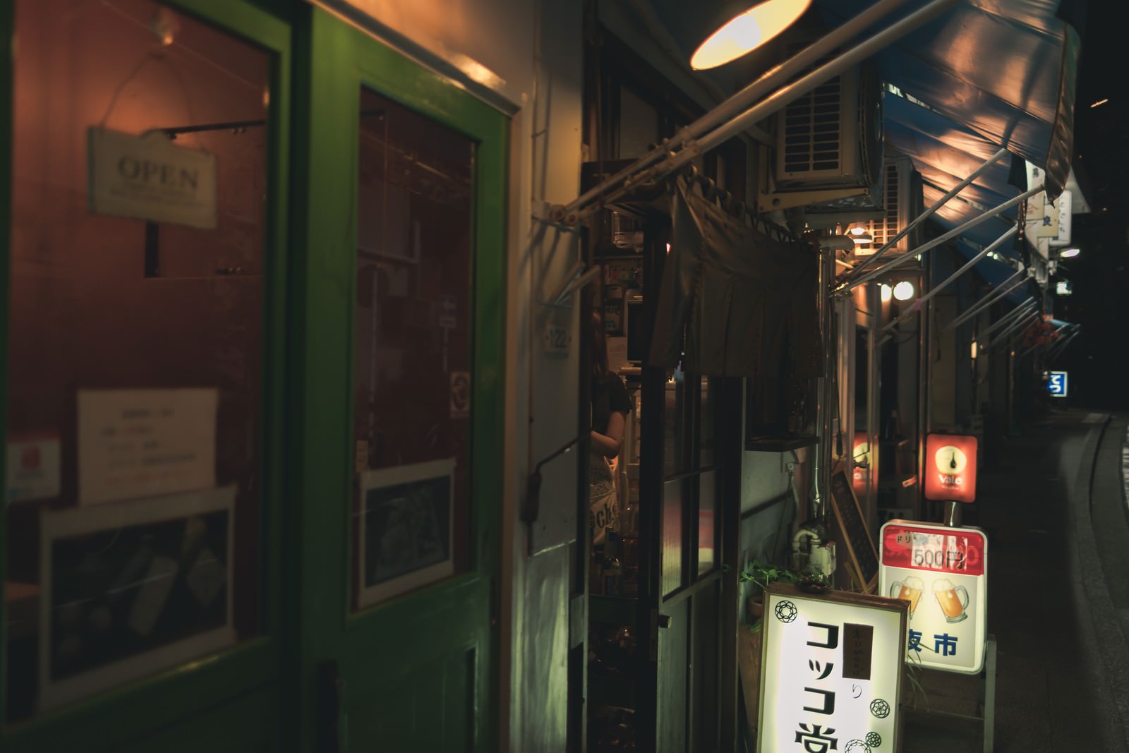 都橋商店街の居酒屋の軒先、緑色の扉とのれんが見える夜の風景