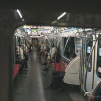 電車の端の座席に座る乗客の写真