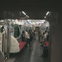 隣の車両から見える電車内の乗客の日常的な風景の写真