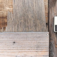 劣化したベニヤ壁に付いた白い玄関チャイムの写真