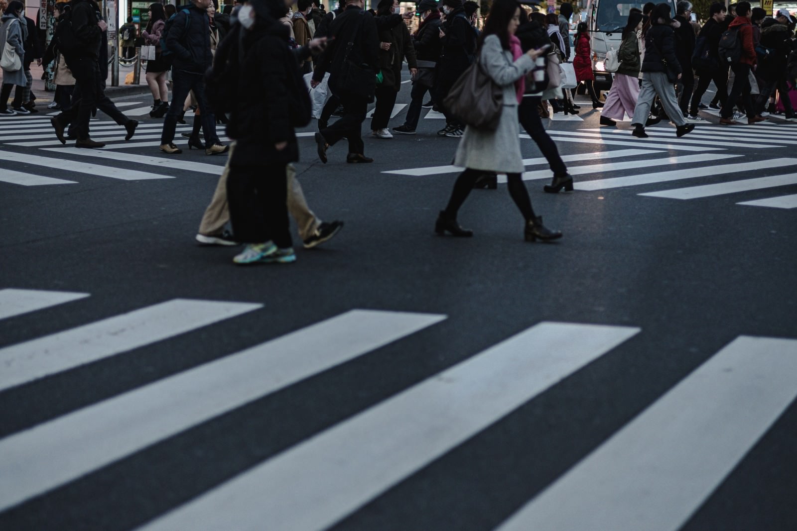 横断歩道を渡る多くの通行人の足元を撮影した写真