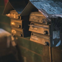 古びて落書きされた郵便受けが並ぶ街角の風景の写真