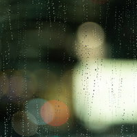 雨の窓ガラス越しに見えるネオンと水滴の玉ボケの写真