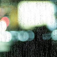 煌めくネオンと雨粒残る窓ガラスの夜景の写真