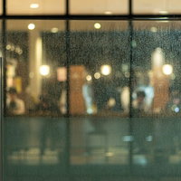 雨降りの日のカフェ、ガラス越しにボケた照明と雨粒の写真