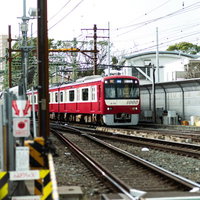 駅のホームから見た京急線の赤と白の電車と線路の写真