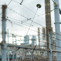 線路脇に続く有刺鉄線フェンスと電柱の風景の写真