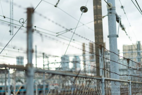 線路脇に続く有刺鉄線フェンスと電柱の風景