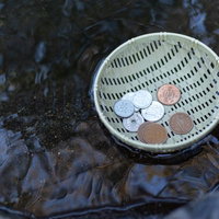 銭洗い中のお金をザルで洗う様子の写真