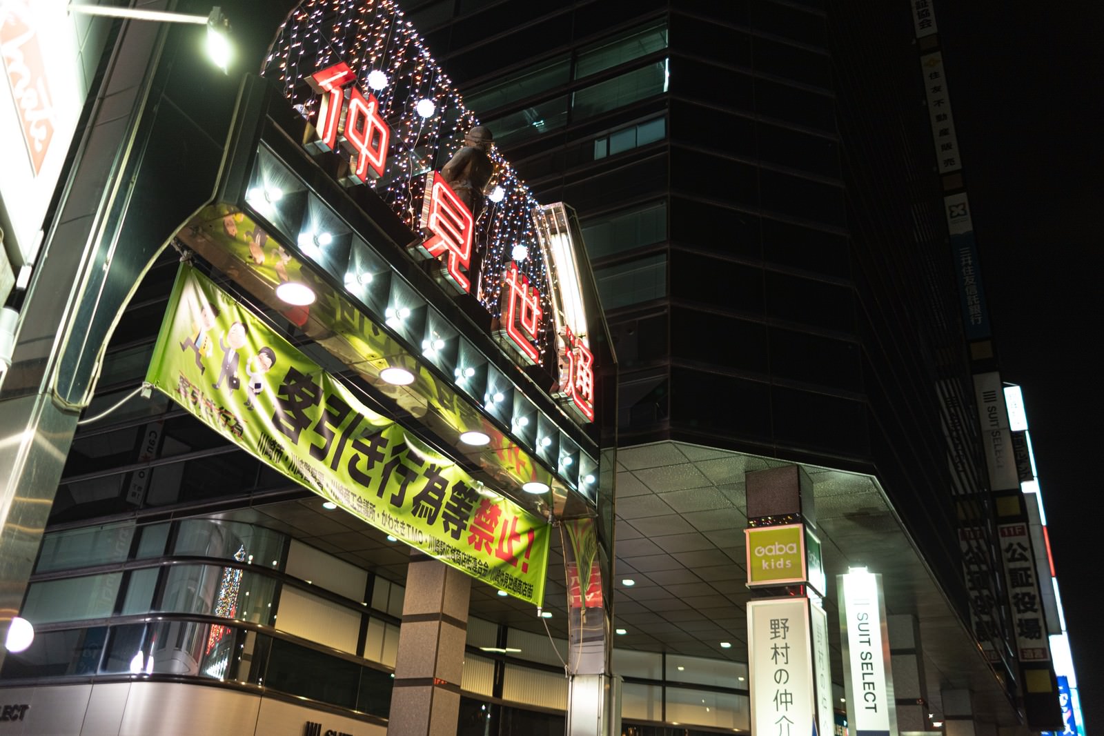 川崎の仲見世通りで夜に光るネオンサインと客引き禁止の横断幕