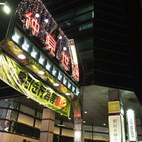 川崎の仲見世通りで光るネオンの看板と客引き禁止の横断幕の写真