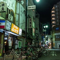 名画通りの路地裏に停まる複数の自転車と街灯の写真