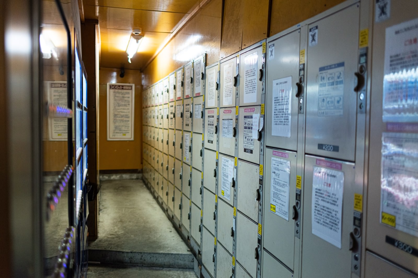 施設内の通路に設置された銀色のコインロッカーと自動販売機