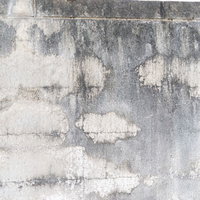 シミと汚れ、ひび割れが目立つ経年劣化したコンクリート表面の写真