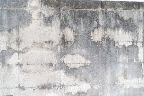 シミと汚れ、ひび割れが目立つ経年劣化したコンクリート表面