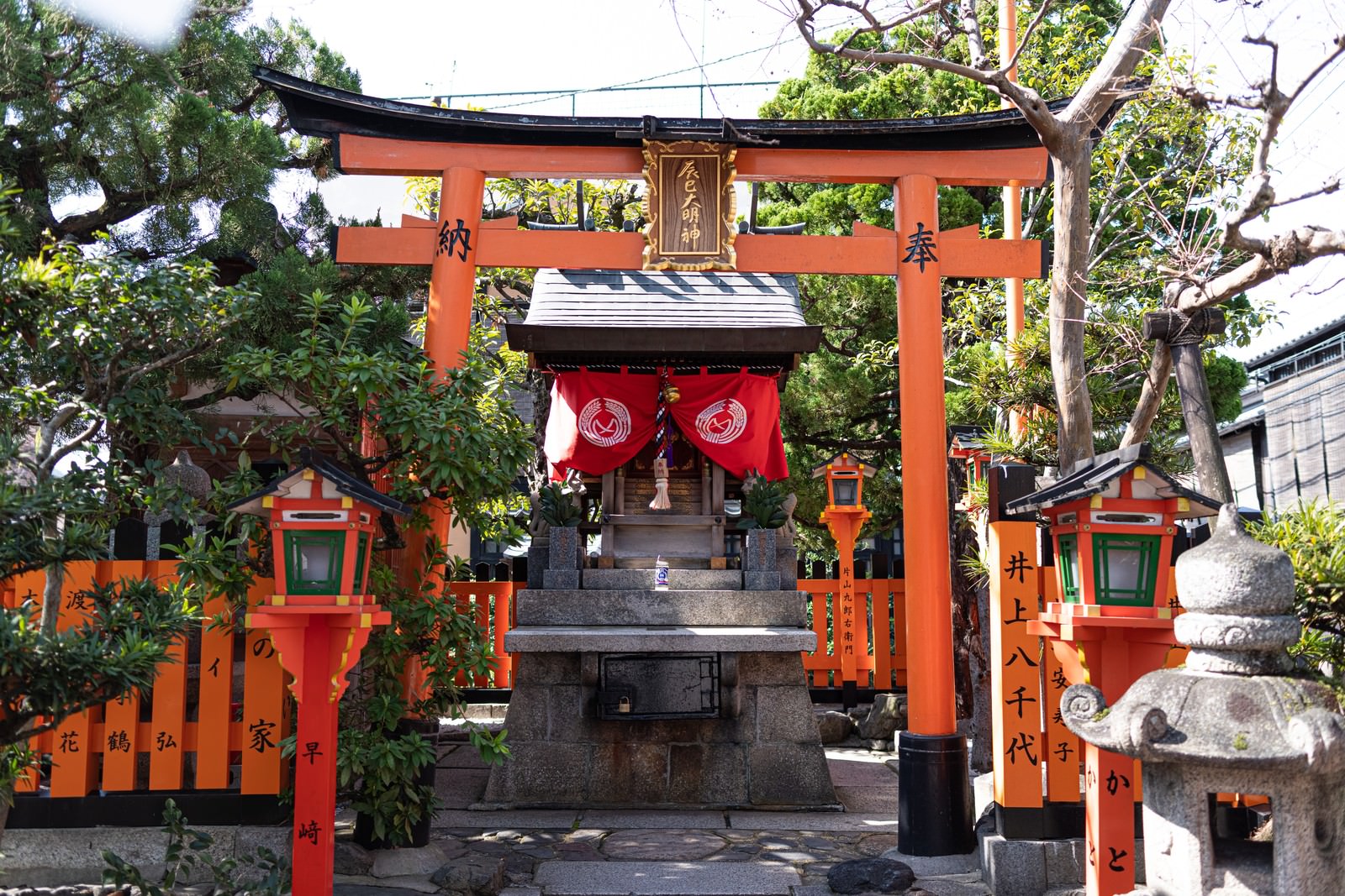 石段の上に建つ辰巳大明神の朱色の鳥居と祠、周囲に提灯が見える