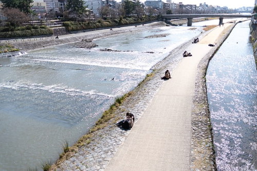 京都の鴨川で昼時にデートするカップルたち
