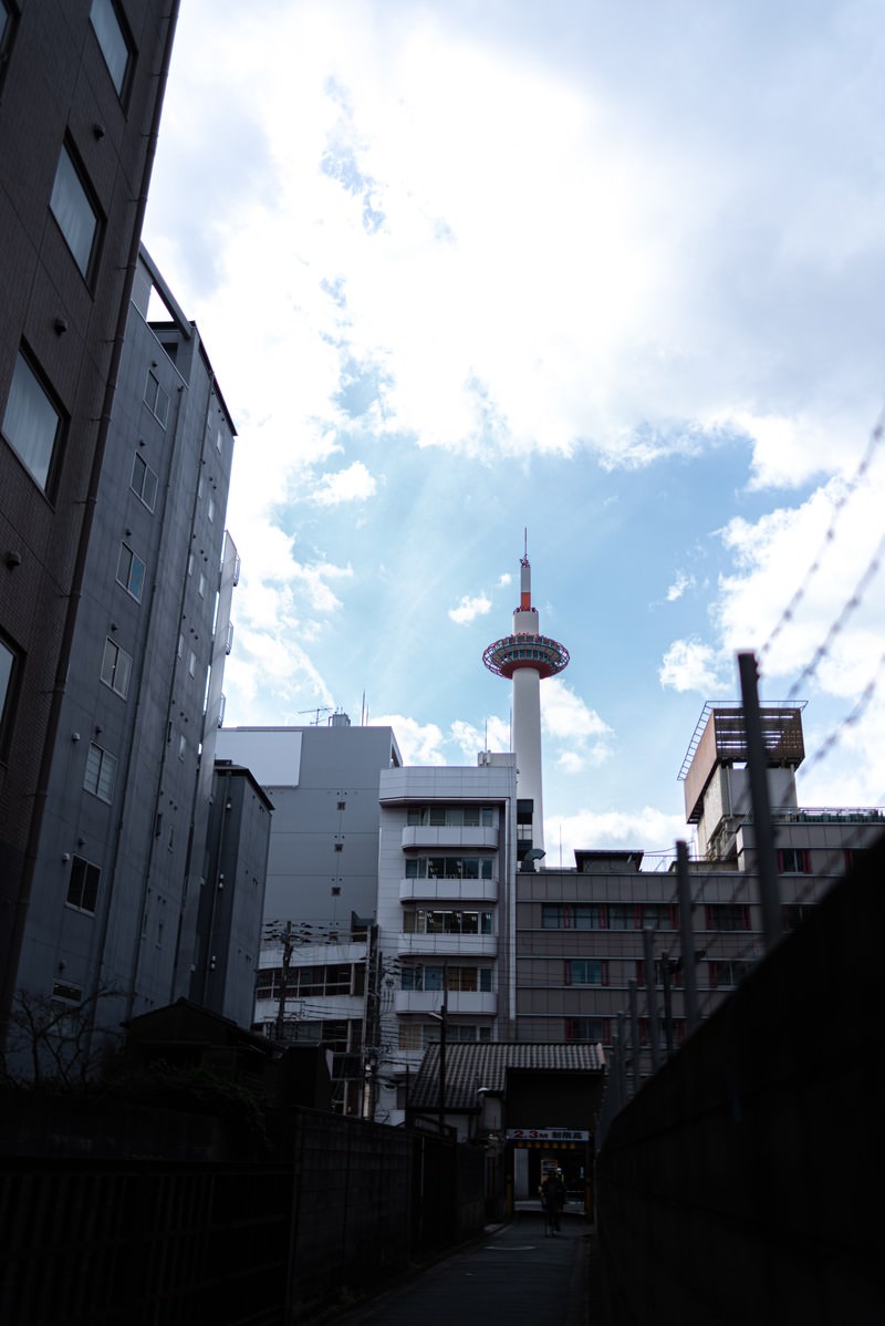 路地裏の奥に見える京都タワーと周辺の建物群