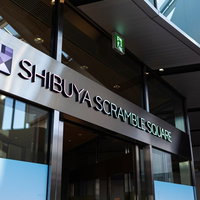 渋谷スクランブルスクエアのガラス張り建物に設置された白い看板の写真