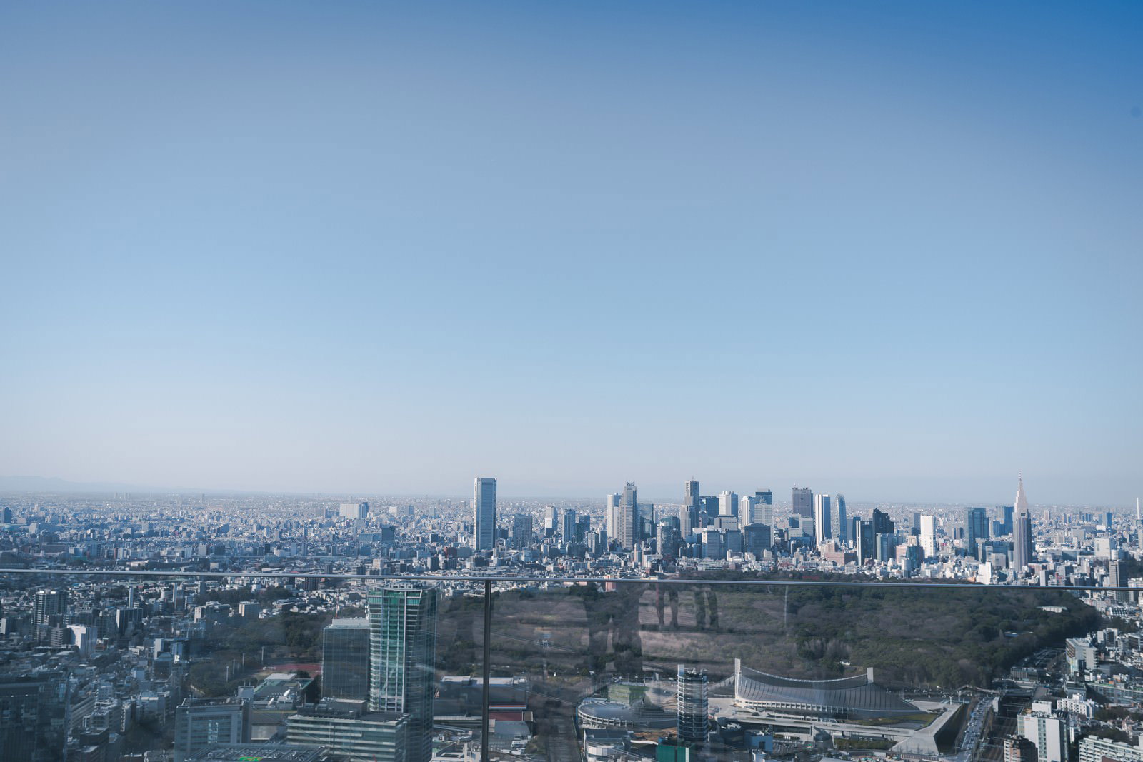 青空の下に広がる都市の街並みと遠方に見える新宿の高層ビル群