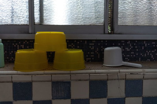 窓沿いに整頓された黄色とグレーの桶