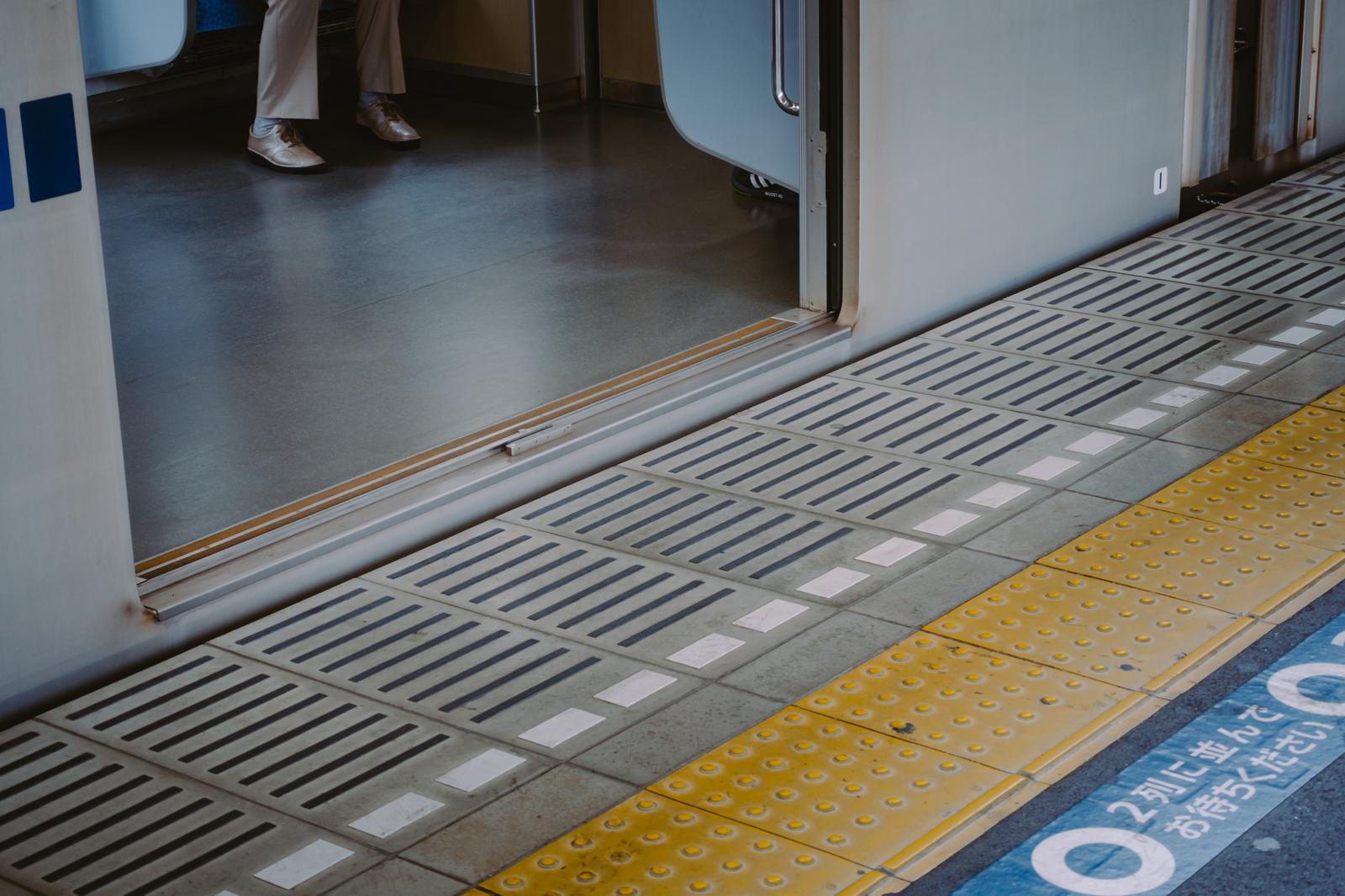 駅のホームで電車が停車。黄色い点字ブロックが敷かれている