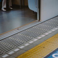 通過待ちホームに停車中の電車内と点字ブロックの写真