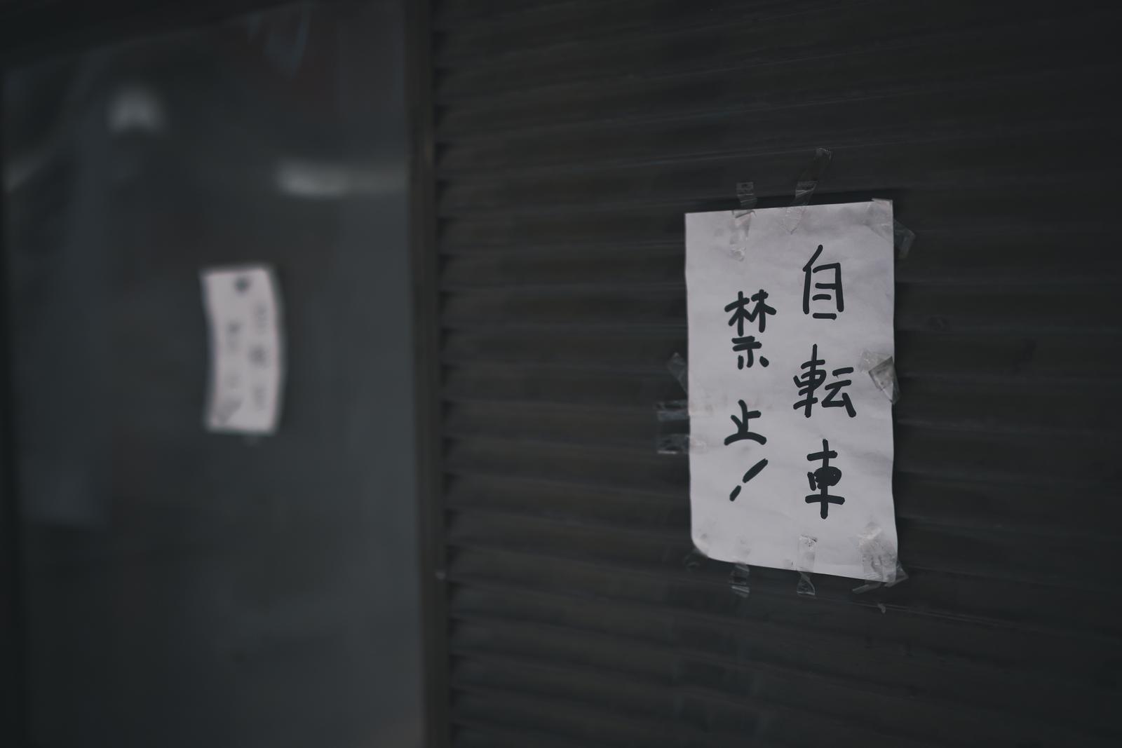 壁に貼られた自転車禁止と駐輪禁止の白い手書き張り紙