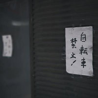 駅前の暗い壁に貼られた自転車禁止と駐輪禁止の張り紙の写真