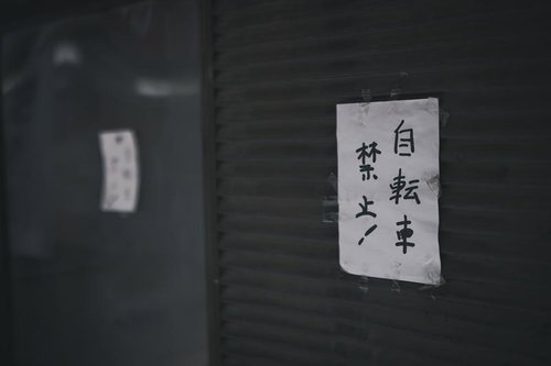 駅前の暗い壁に貼られた自転車禁止と駐輪禁止の張り紙