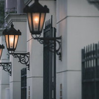 アンティークな雰囲気の街灯、夕暮れ時の温かい光が灯る歴史的な街並みの写真