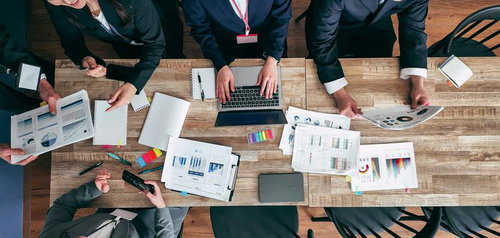 紙の資料とパソコンを用いてディスカッションする会議