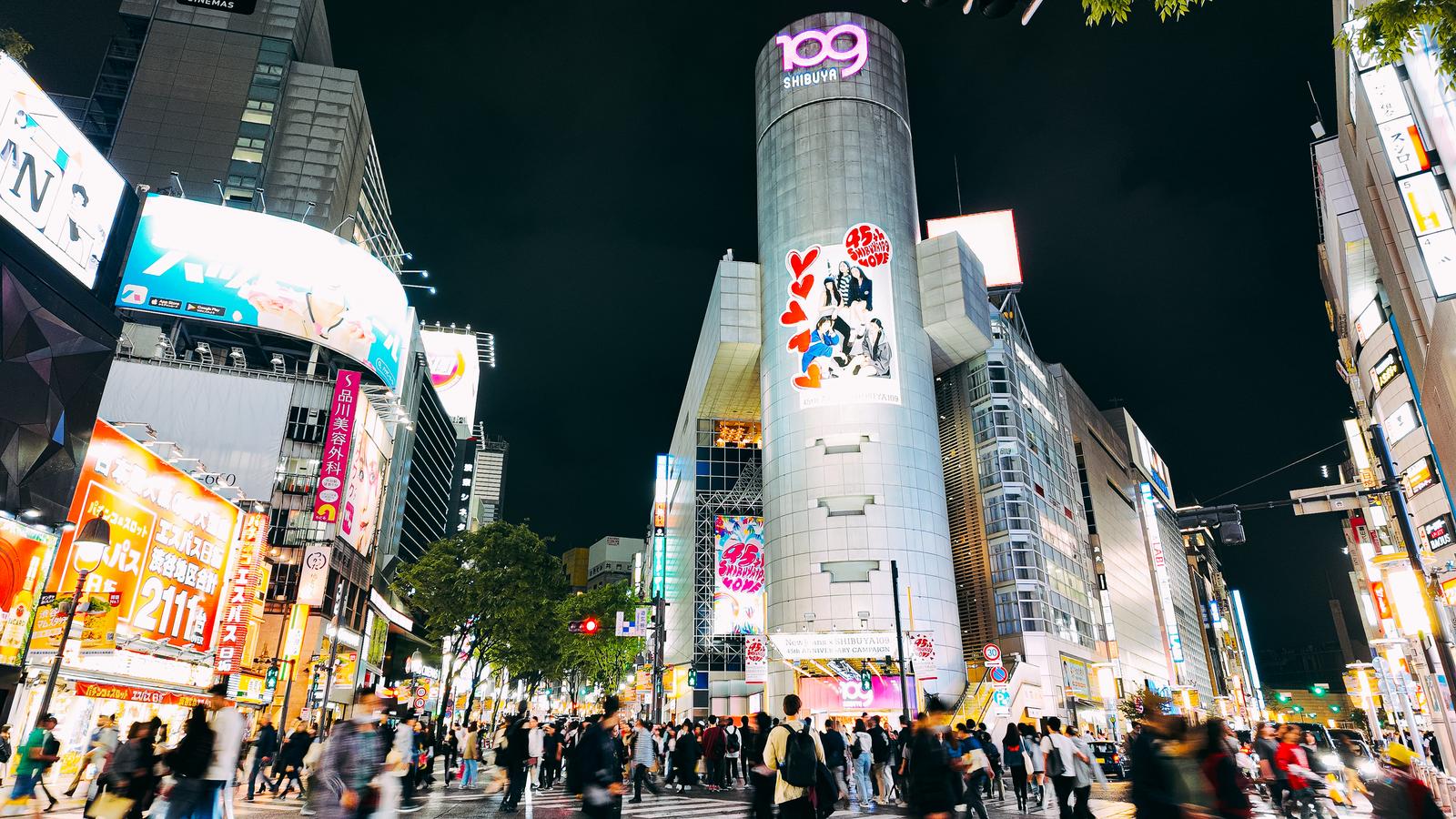 渋谷109前で多くの人が行き交う横断歩道と、ネオン看板が光る繁華街の夜景