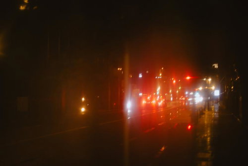 傘越しに見るテールランプと赤信号、雨の夜道の風景