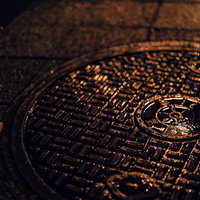 マンホール上の水滴と夜の濡れた路面の写真