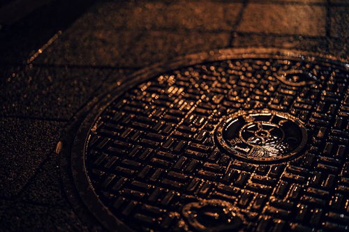 マンホール上の水滴と夜の濡れた路面