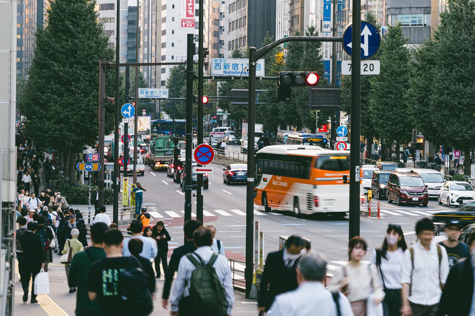 西新宿一丁目の交差点を行き交う歩行者と車、高層ビルが見える都市風景
