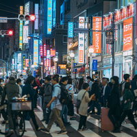 夜間の新大久保駅前を行き交う人混みと横断歩道の写真