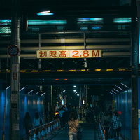 夜間の架線下で2.8M制限高の標識が掲げられた駅前通路の写真