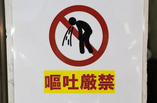 嘔吐厳禁と書かれた赤い禁止マークの警告標識