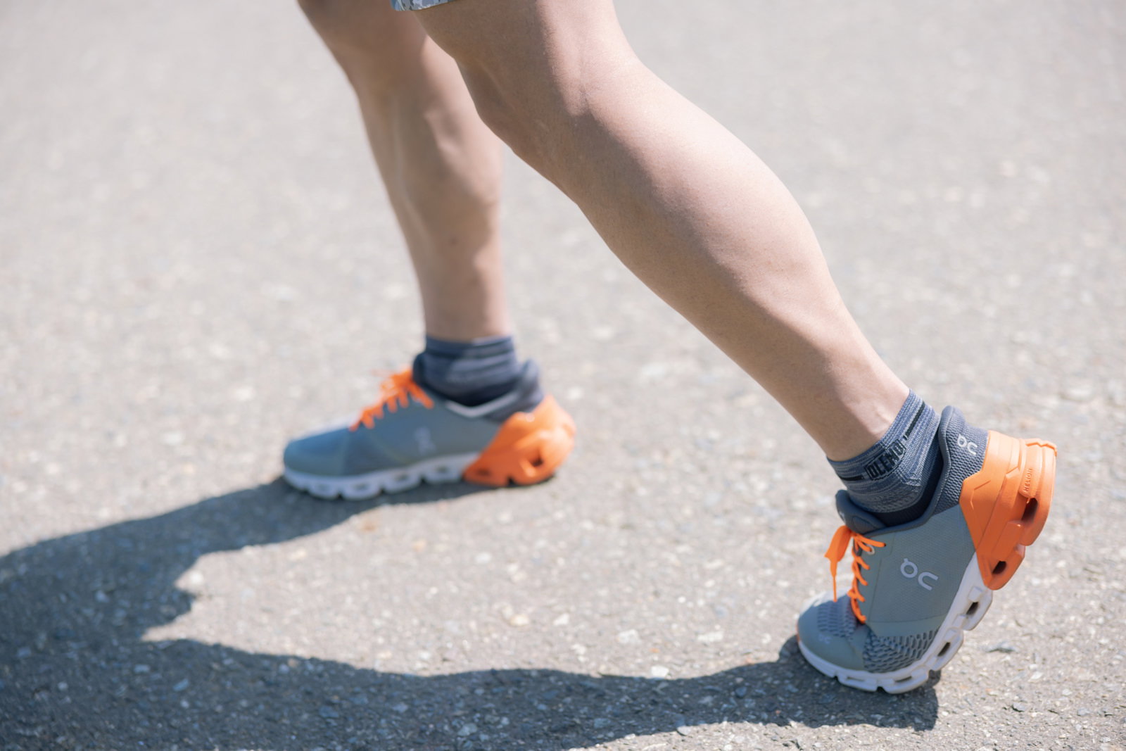 オレンジ色のアクセントが入ったランニングシューズを履いて走る男性の足元［モデル：うえせい］
