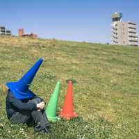 青いパーカーを着た三角コーンが河川敷で座り込む気分の写真