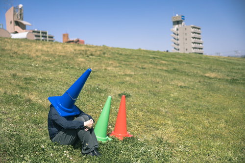 青いパーカーを着た三角コーンが河川敷で座り込む気分