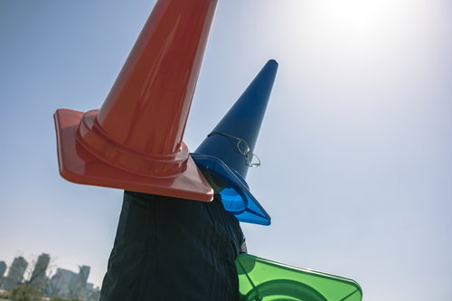 青空の下でカラーコーンを被った怪人△コーンマン