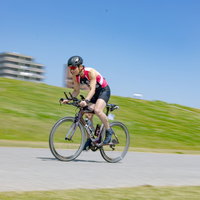 ヘルメット着用で自転車を走行するトライアスリートの男性の写真